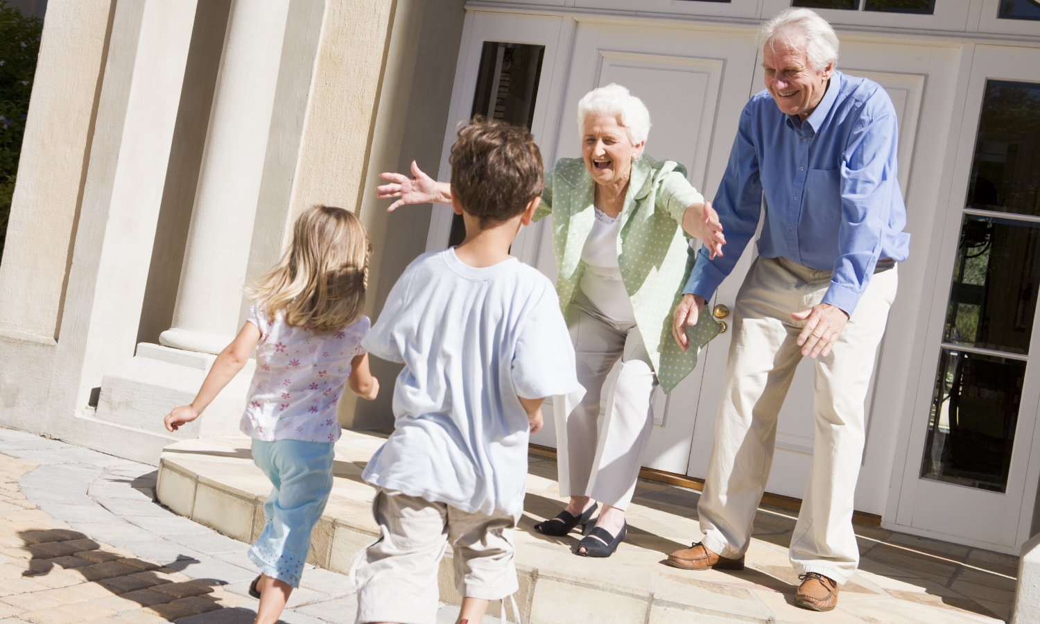 Grandparents playing with grandchildren outside a house